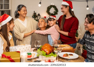 Asian kid hugging grandparent while celebrate Christmas party in house. Attractive family spending leisure free time on holiday vacation to celebrate Thanksgiving, X-mas eve on dining table at home. - Powered by Shutterstock