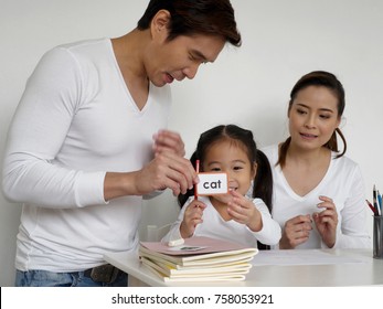 Asian Kid Learning English With Her Father And Mother At Home