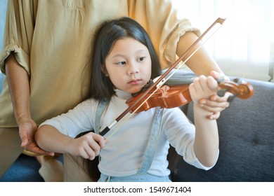 Asian Kid Learning And Practising  To Play Violin At Home