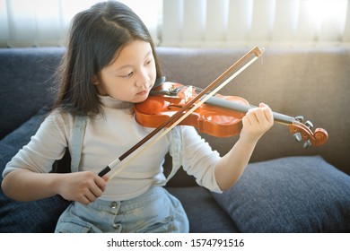 Asian Kid Learning And Practising  To Play Violin At Home