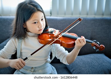 Asian Kid Learning And Practising  To Play Violin At Home