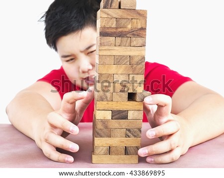 Asian kid is playing wood blocks tower game for practicing physical and mental skill. Photo is focused at model hands and isolated over white.