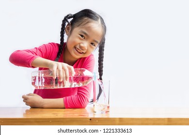 Asian Kid Is Pouring Water Into A Glass. Water Necessary For The Growth Of The Children.