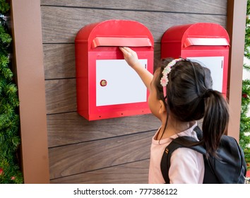 Asian Kid Sending Her Mail In The Red Metal Mailbox Hanging On Wood Wall