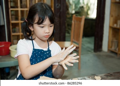 Asian Kid Shaping Pottery In The Studio