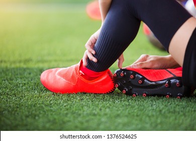 Asian kid soccer player is sitting and catch the soles of the feet because of pain, soccer player was injured in the foot with pain during competition or practice - Powered by Shutterstock