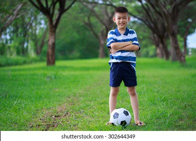 Asian Kid Standing With Soccer Ball In The Park