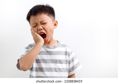 Asian Kid Suffering From Toothache Pain, Holding His Cheek, Isolated On White Background. Dental Health And Care Concept.