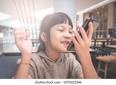 Asian Kid Is Talking On Speaker Phone In Cafe