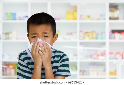 Asian Kid With The Tissue, Blur Image Of Drugstore As Background.