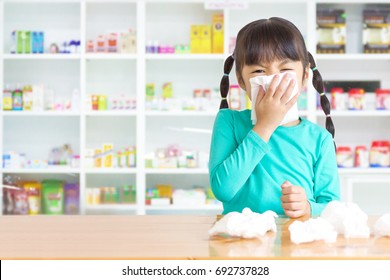 Asian Kid With The Tissue, She Got A Cold Have A Drugstore As Background.