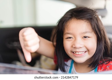 Asian Kid Tween Girl Thumb Down With Smile On Seat.Family Riding Car Traveling Automobile. Asian Family Parenting And Children With Funny Face.Angry Selfish Child.Sibling Kid.spoiled Child.bad Feel.