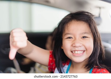 Asian Kid Tween Girl Thumb Down With Smile On Seat.Family Riding Car Traveling Automobile. Asian Family Parenting And Children With Funny Face.Angry Selfish Child.Sibling Kid.spoiled Child.bad Feel.