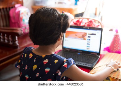 Asian Kid Using Laptop In Computer Classroom At Primary School. Cute Child Typing Computer At Home. Home School Concept.