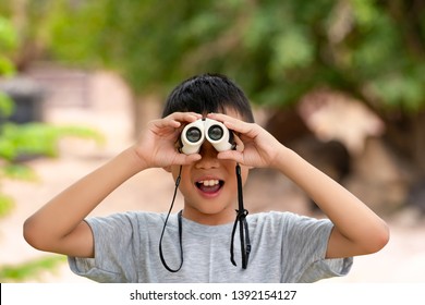 Asian Kids Boy Playing And Looking On Telescope In Zoo Park Nature, Blurred Nature Background, Kid Child Smiling For Watching, Wearing Gray Shirt In Journey Outdoor On Summer Holiday
