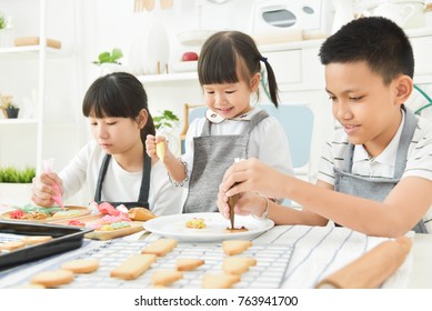 Asian Kids Decorating Cookies In The Kitchen.