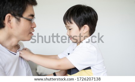 Asian kids learning Buttoned shirt with father