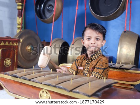 Asian kids playing the Gamelan with batik clothes. Gamelan is a musical instrument typical of Indonesia, Central Java