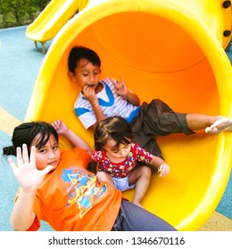 Asian kids resting at the end of the slide on the playground. - Shutterstock ID 1346670116