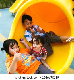 Asian kids resting at the end of the slide on the playground. - Shutterstock ID 1346670119