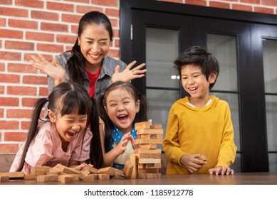 Asian Kids And Their Teacher Are Playing Wooden Blocks Stack Game In Classroom At The School Together. Falling.