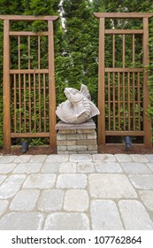 Asian Koi Fish Stone Sculpture In Garden Backyard Paver Patio With Trellis Background