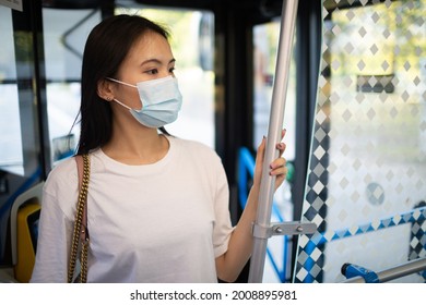 Asian Korean or Japanese Woman take a ride stand in public transport bus or tram with face mask - Powered by Shutterstock