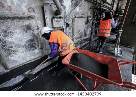 Asian labor with shovel cleanout sewage in the sewer at cement factory. Hard work concept.