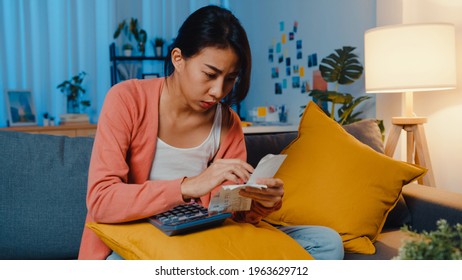 Asian Lady Feel Stress And Worried With Bill And Invoice Credit Card Calculating Loan On Sofa At Home. Home Loan Stress, Get Loan No Job,  Coronavirus Hardship Loans, Can't Make Loan Payment Concept.