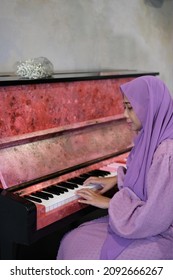An Asian lady sit beside the piano
