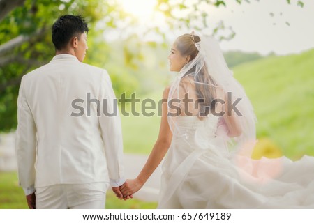 Asian lady in wedding dress run with her husband, out door pre wedding activity, marriage and wedding concept