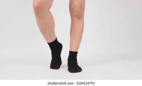 Asian leg and foot wear black sock and tip toe one leg on white background. isolated