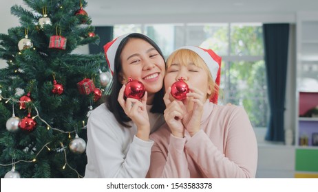 Asian Lesbian Couple Celebrate Christmas Festival. LGBTQ Female Teen Wear Christmas Hat Relax Happy Play Christmas Ball Enjoy Xmas Winter Holidays Together In Living Room At Home.