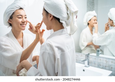 Asian lesbian gay couple putting smooth and skin care for facial soft. Attractive funny woman friend touches on face and apply cream lotion together after shower. Beauty, skin care and health concept. - Powered by Shutterstock