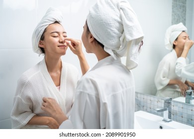 Asian lesbian gay couple putting smooth and skin care for facial soft. Attractive funny woman friend touches on face and apply cream lotion together after shower. Beauty, skin care and health concept. - Powered by Shutterstock