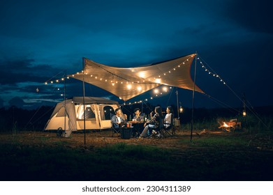 Asian LGBTQ+ couple drinking and barbecue in a romantic camping setting. Groups of friends and couples having a drink party in a camping atmosphere amidst forests and rivers. - Powered by Shutterstock