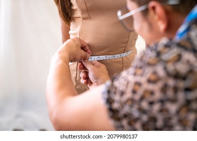 Asian LGBTQ Guy Designer Bridal Shop Owner Measuring Female Bride Customer For Making Wedding Gown In Fitting Room At Wedding Studio. Small Business Tailor Entrepreneur And Wedding Planner Concept