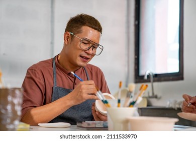 Asian LGBTQ guy learning color painting self  made pottery mug and friends at home  Confidence male enjoy handicraft activity lifestyle hobbies ceramic sculpture painting workshop at pottery studio