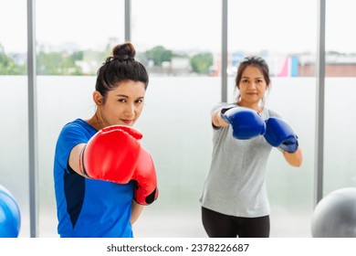 Asian lifestyle adult and young woman smiling sports fitness boxer wearing gloves practicing kick on boxing in sportswear work out indoor yoga studio, sport healthy workout concept - Powered by Shutterstock