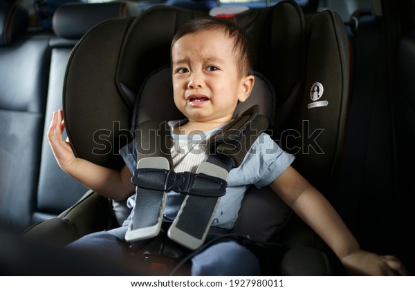 Asian little baby crying and sad while fastened belt\
and seat in the safety car seat. A boy worry, fear and unhappy in a\
car.