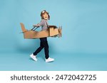 Asian little boy aviator playing and running with cardboard airplane isolated on blue sky background, Kid toy diy concept