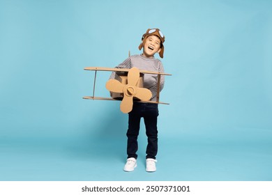 Asian little boy aviator playing with cardboard airplane isolated on blue sky background, Kid toy diy concept - Powered by Shutterstock