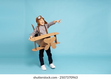 Asian little boy aviator pointing and playing with cardboard airplane isolated on blue sky background, Kid toy diy concept - Powered by Shutterstock