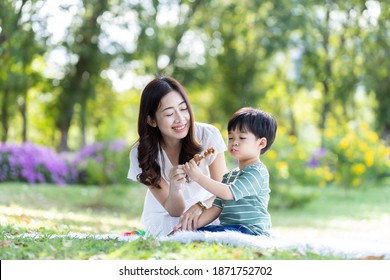 Asian little boy eating meal with his mother on in the park. Young mother and little son spending time together on holiday in the garden. Happy family and holiday - Powered by Shutterstock