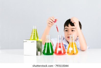 Asian Little Boy Having Fun In The Liquid Droplets Red Into The Test Beaker On White Table And Background,  Easy Science Experiment For Children, Education Concept