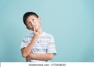 Asian little boy standing thinking on blue background isolated, Asia man look up and copy space	