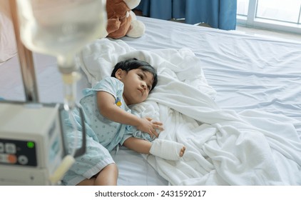 Asian little child boy patient lying down on bed and hand still lock with equipment medical for injection for saline or vitamin or infusion intravenous - Powered by Shutterstock