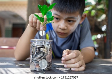 Asian Little Child Boy Putting Coin Into Glass Bottle In The Garden. Kid Saving Money For The Future Concept