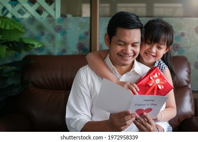 Asian Little Child Daughters Congratulating Dad And Giving Him Postcard And Gift Box With Smiling And Hugging.Concept Of Happy Father's Day