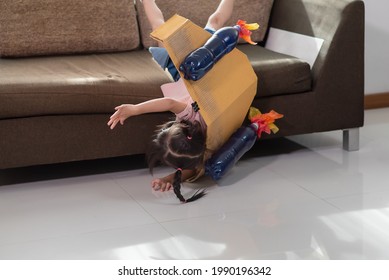 Asian little child girl accident falling off the couch after playing in an astronaut costume